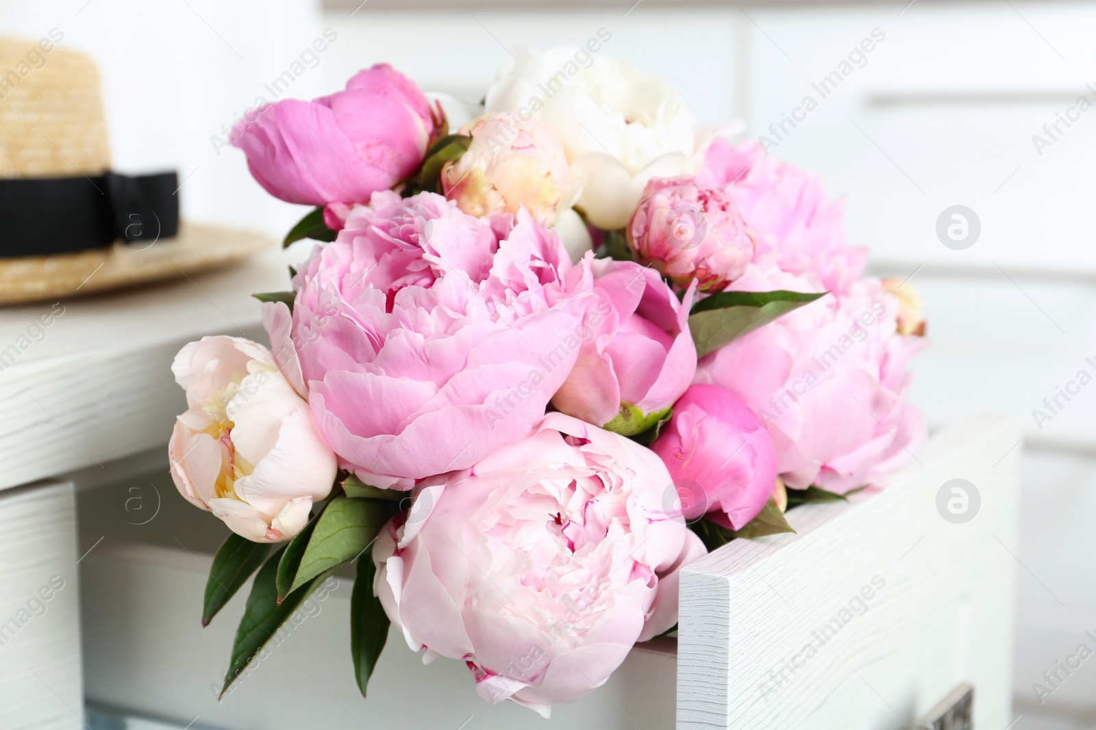 Photo of Bouquet of beautiful peonies in commode drawer indoors