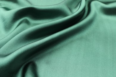 Photo of Crumpled green silk fabric as background, closeup