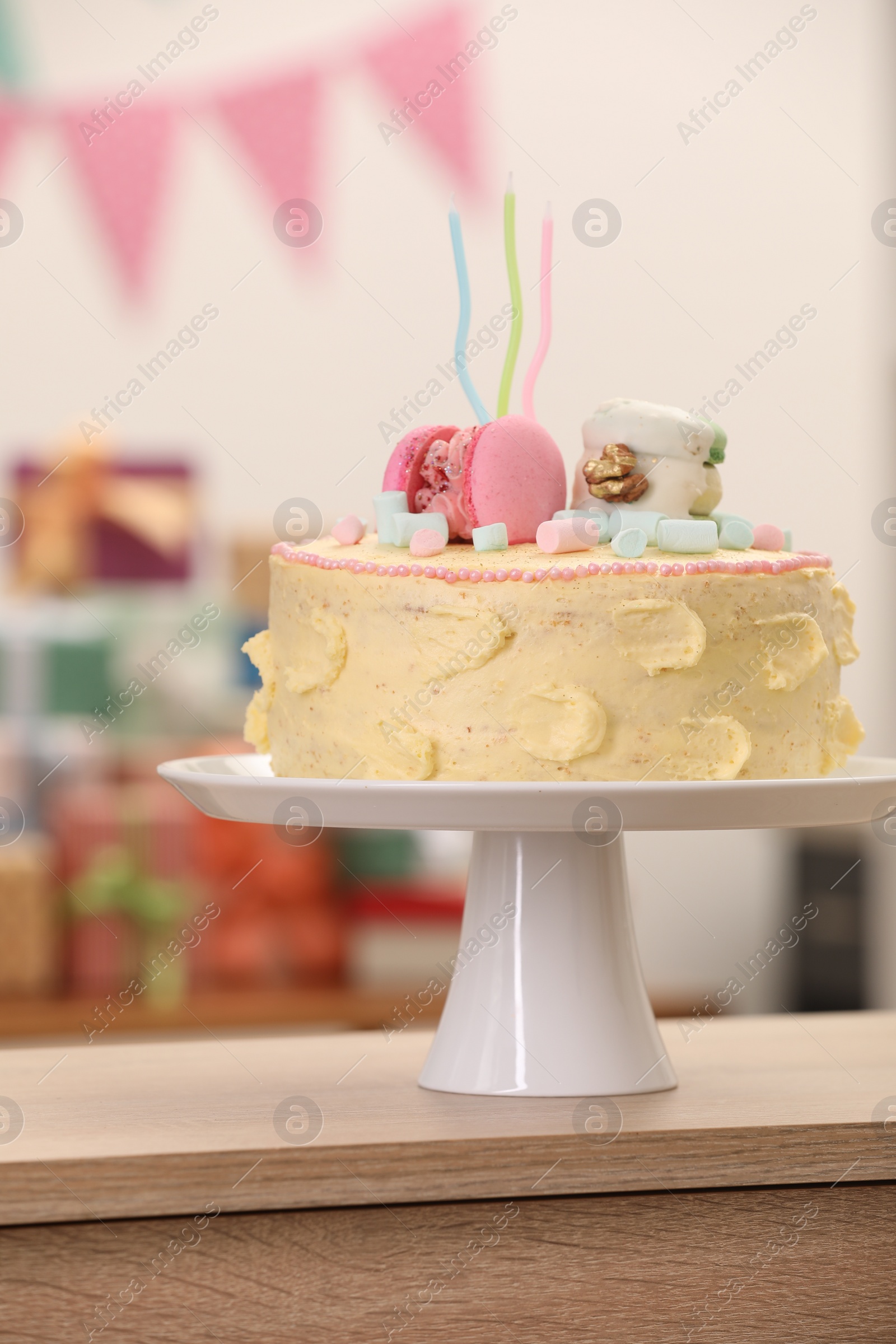 Photo of Delicious cake decorated with macarons and marshmallows on wooden table against blurred background