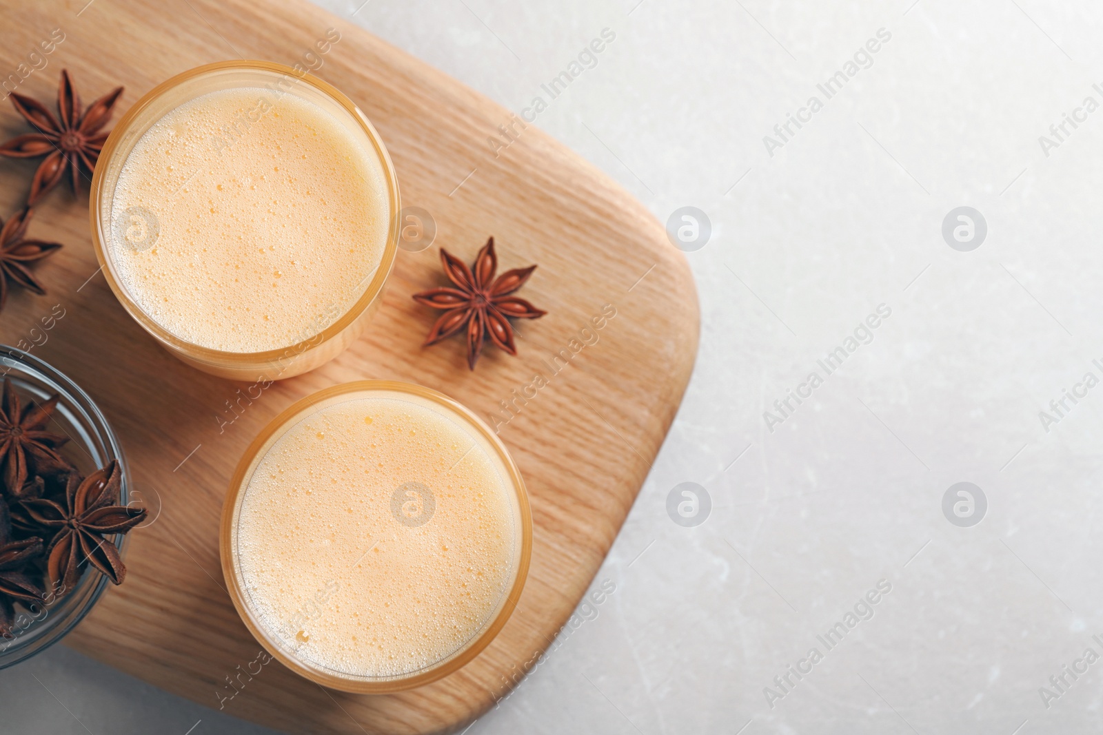 Photo of Glasses of delicious eggnog with anise on grey marble table, top view. Space for text