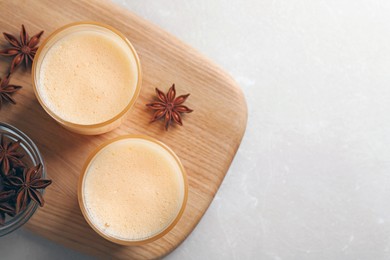 Glasses of delicious eggnog with anise on grey marble table, top view. Space for text