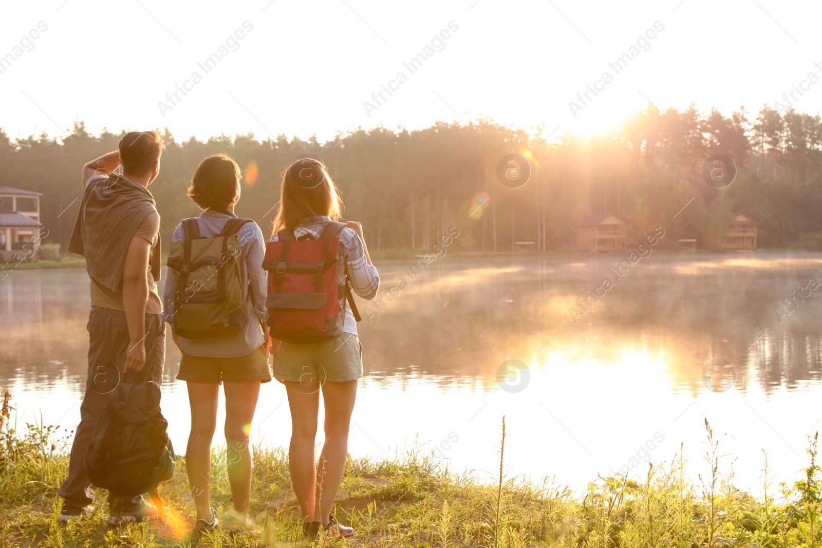 Photo of Young friends on shore of beautiful lake. Camping season