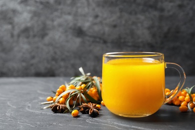 Photo of Sea buckthorn tea and fresh berries on grey table