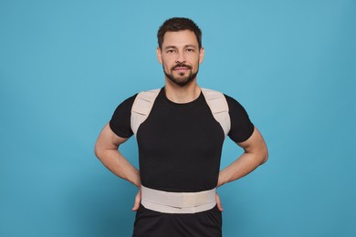 Handsome man with orthopedic corset on blue background