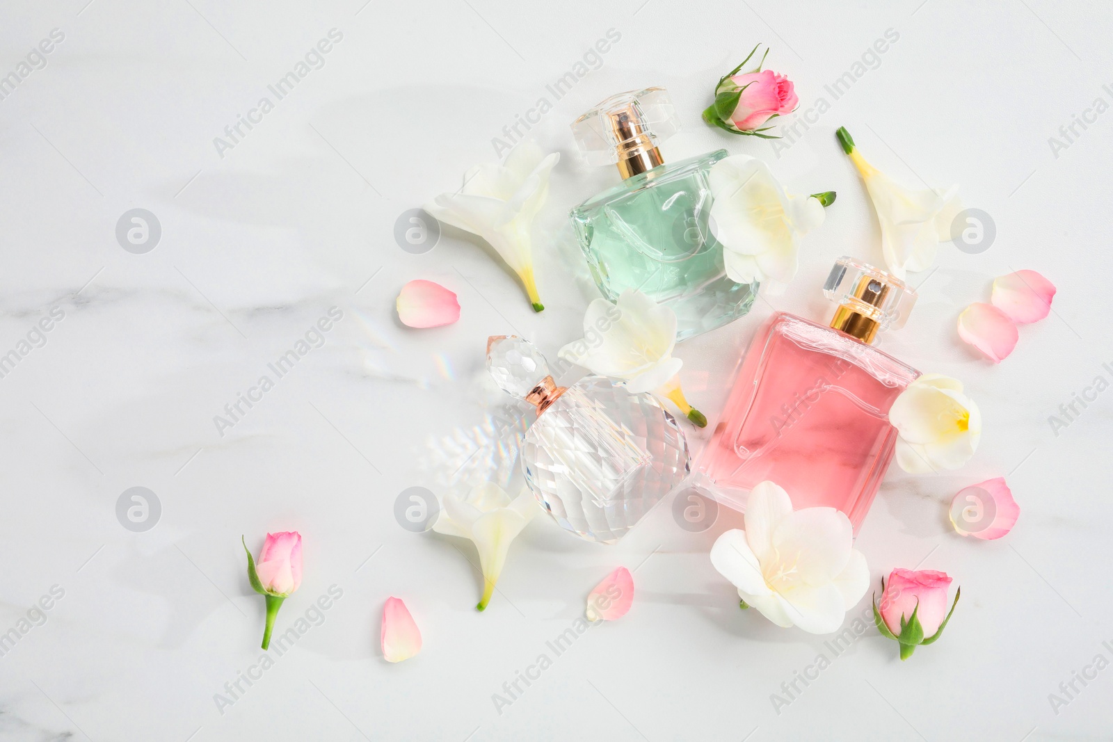 Photo of Luxury perfume and floral decor on white marble table, flat lay. Space for text