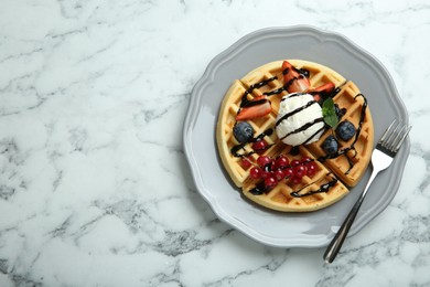 Photo of Delicious Belgian waffles with ice cream, berries and chocolate sauce on light marble table, top view. Space for text