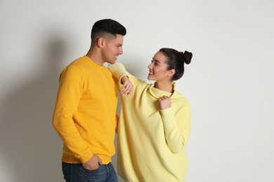 Happy couple wearing yellow warm sweaters on white background