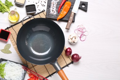 Photo of Wok, chopsticks and different products on white wooden table, flat lay. Space for text