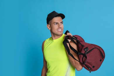 Photo of Handsome man with sports bag on light blue background