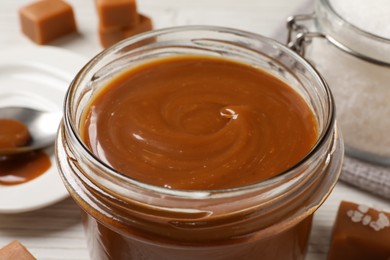 Photo of Yummy salted caramel in glass jar on table, closeup