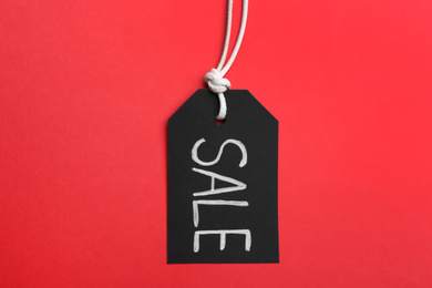 Photo of Tag with word SALE on red background, top view. Black Friday concept