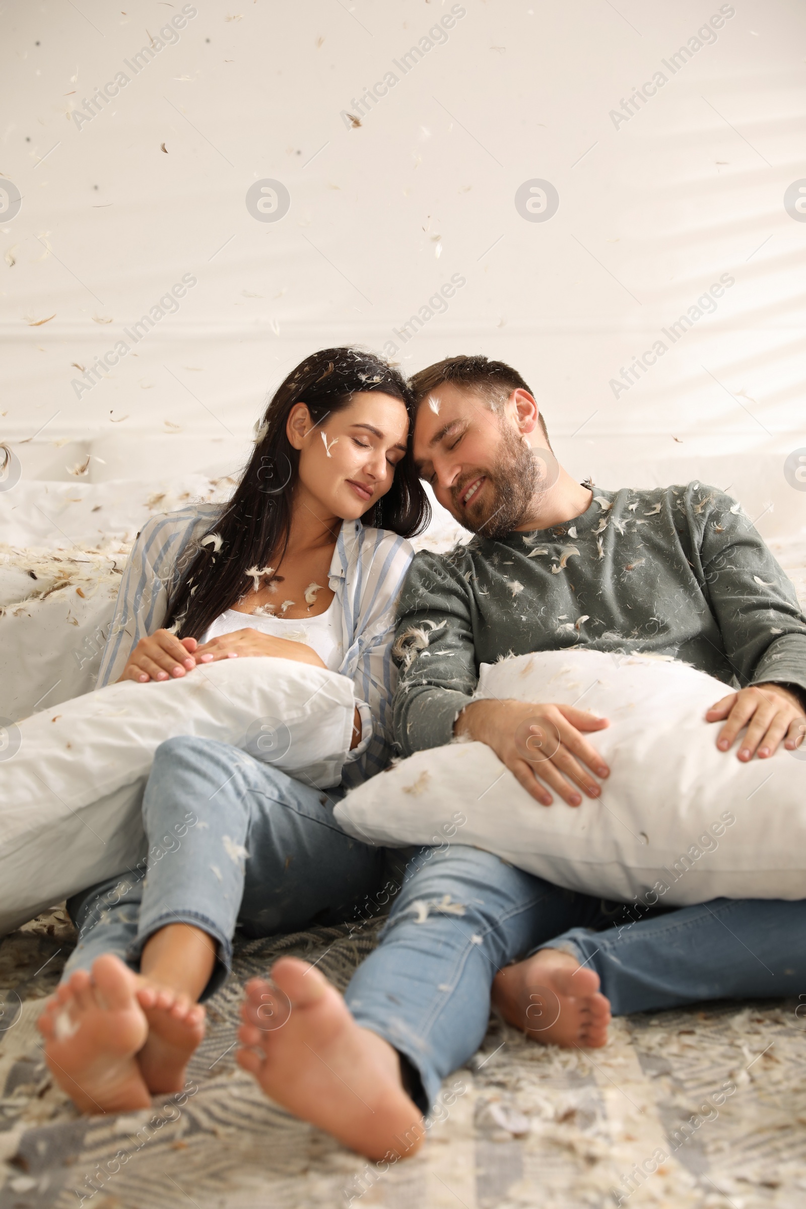 Photo of Happy young couple resting after fun pillow fight in bedroom