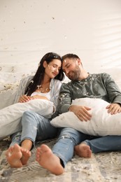 Happy young couple resting after fun pillow fight in bedroom