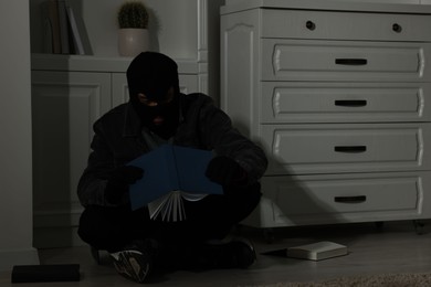Photo of Thief looking for money near chest of drawers at foreign house. Burglary