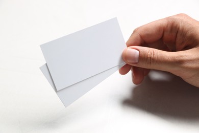 Photo of Man holding blank cards at white table, closeup. Mockup for design