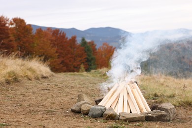 Photo of Bonfire with smoldering firewood in mountains. Camping season