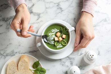 Photo of Woman eating fresh vegetable detox soup with croutons at table, top view