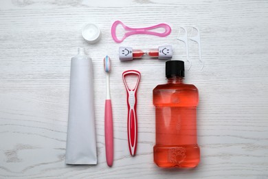 Photo of Flat lay composition with tongue cleaners and teeth care products on white wooden table