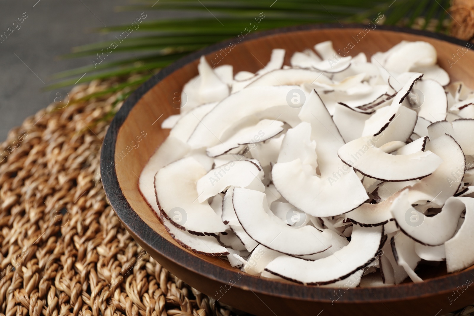 Photo of Tasty coconut chips on wicker mat, closeup