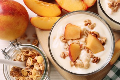 Photo of Delicious yogurt with fresh peach and granola on white table, flat lay