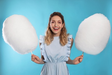 Portrait of pretty young woman with cotton candy on blue background