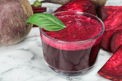 Glass with fresh healthy beet juice on table