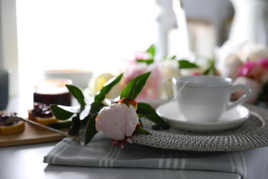 Photo of Beautiful peony and breakfast on table indoors