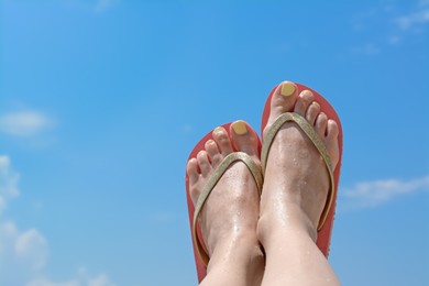 Photo of Woman in stylish pink flip flops against blue sky, closeup of feet. Space for text