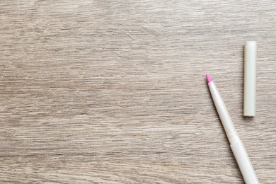 Photo of Lip pencil on wooden table, flat lay with space for text. Cosmetic product