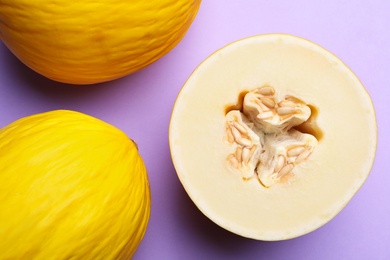 Ripe tasty melons on violet background, flat lay