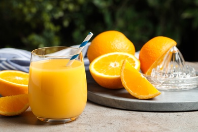 Photo of Glass of orange juice and fresh fruits on grey table