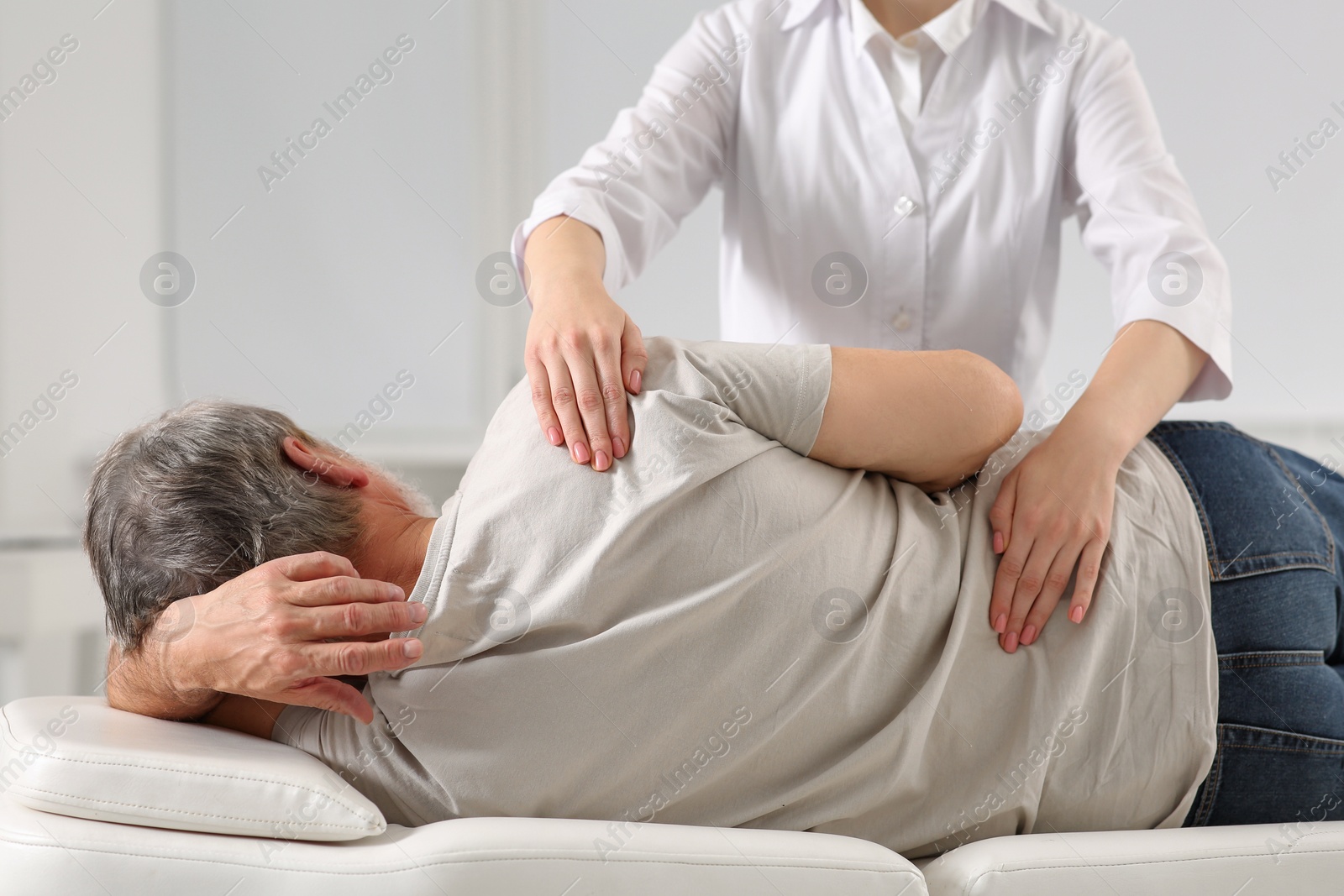 Photo of Professional orthopedist examining patient's back in clinic, closeup