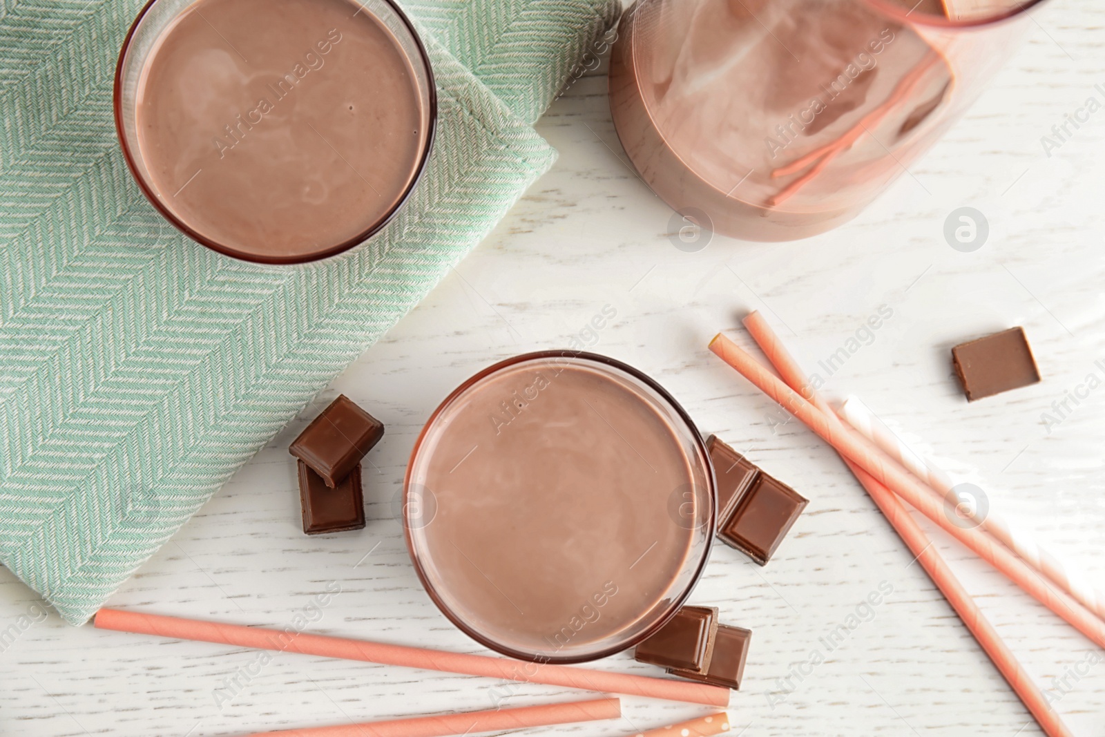 Photo of Flat lay composition with glasses of tasty chocolate milk on wooden background. Dairy drink