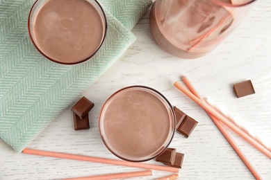 Photo of Flat lay composition with glasses of tasty chocolate milk on wooden background. Dairy drink