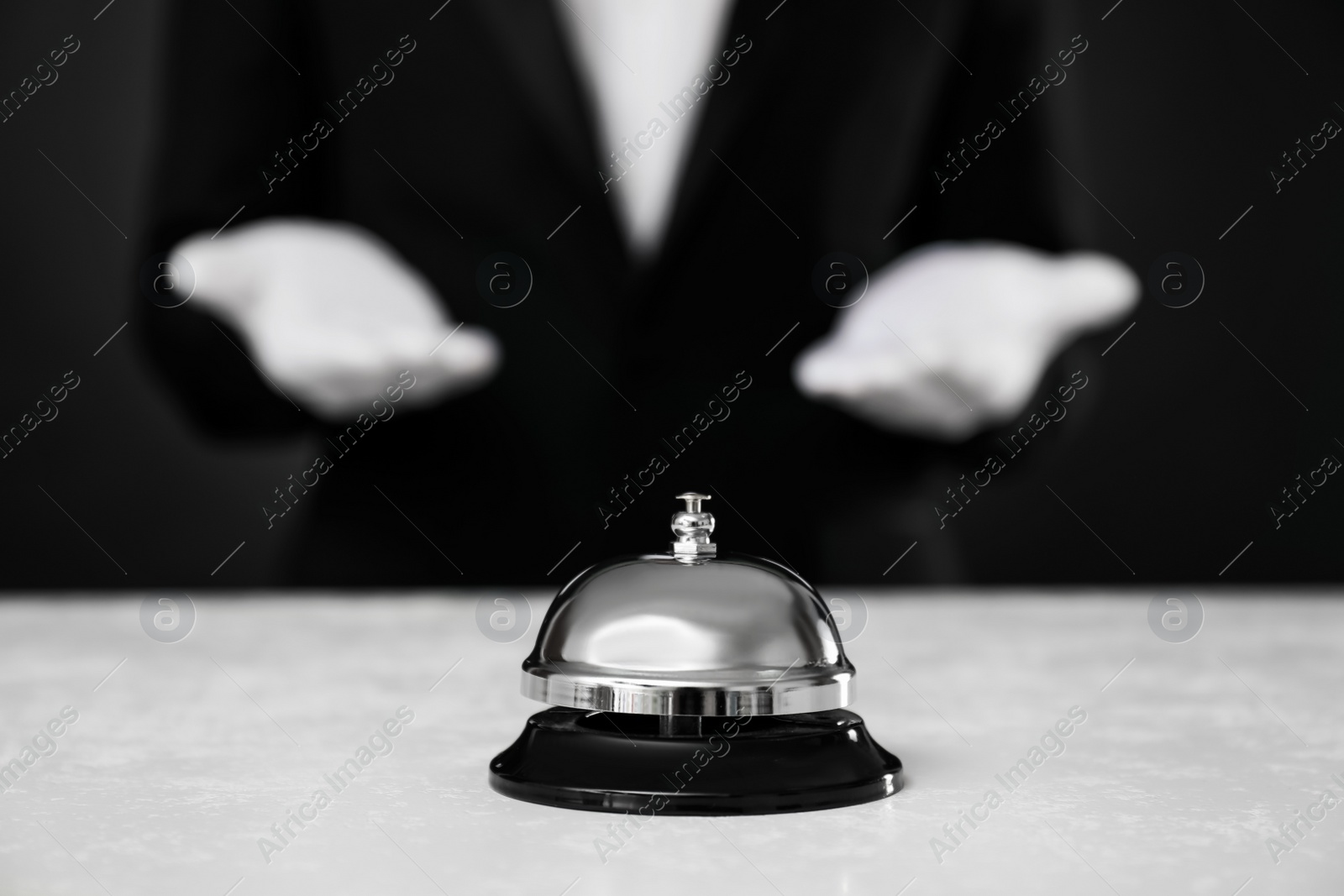 Photo of Butler at white desk with service bell, closeup view