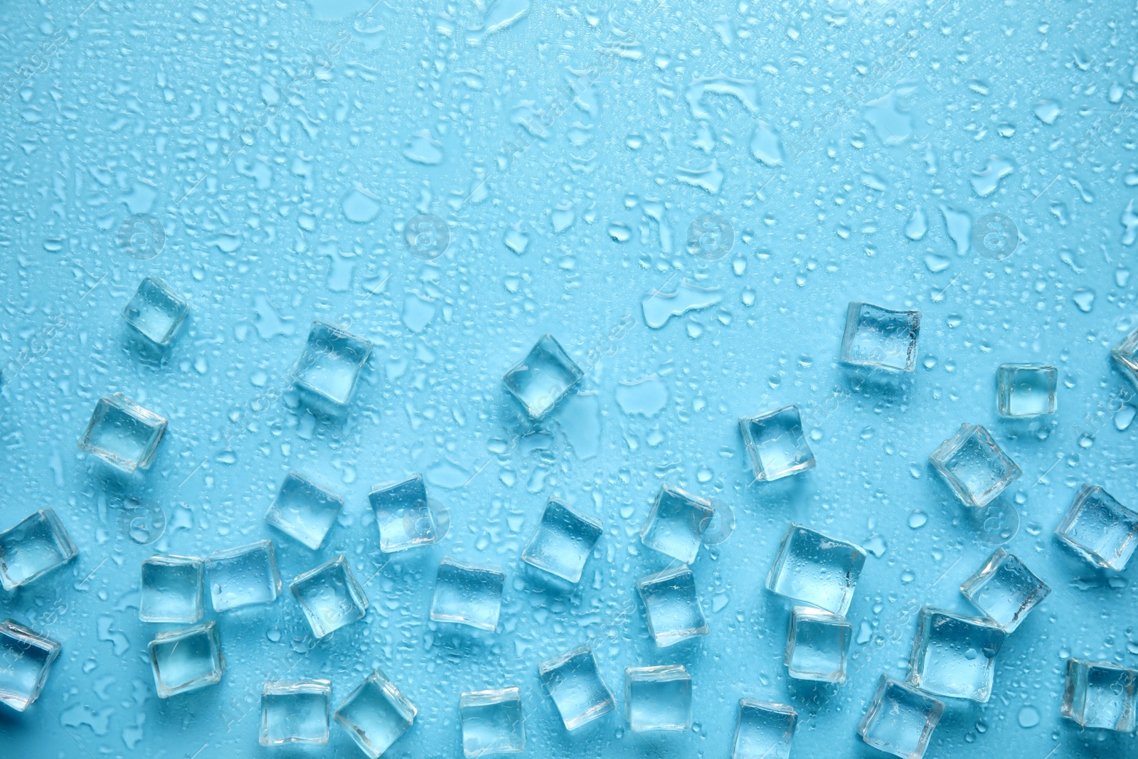 Photo of Ice cubes, water drops and space for text on turquoise background, flat lay. Refreshing drink ingredient