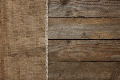 Photo of Burlap fabric on wooden table, top view. Space for text