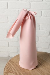 Photo of Furoshiki technique. Gift packed in pink fabric on wooden table