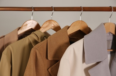 Photo of Different warm coats on rack against light grey background, closeup