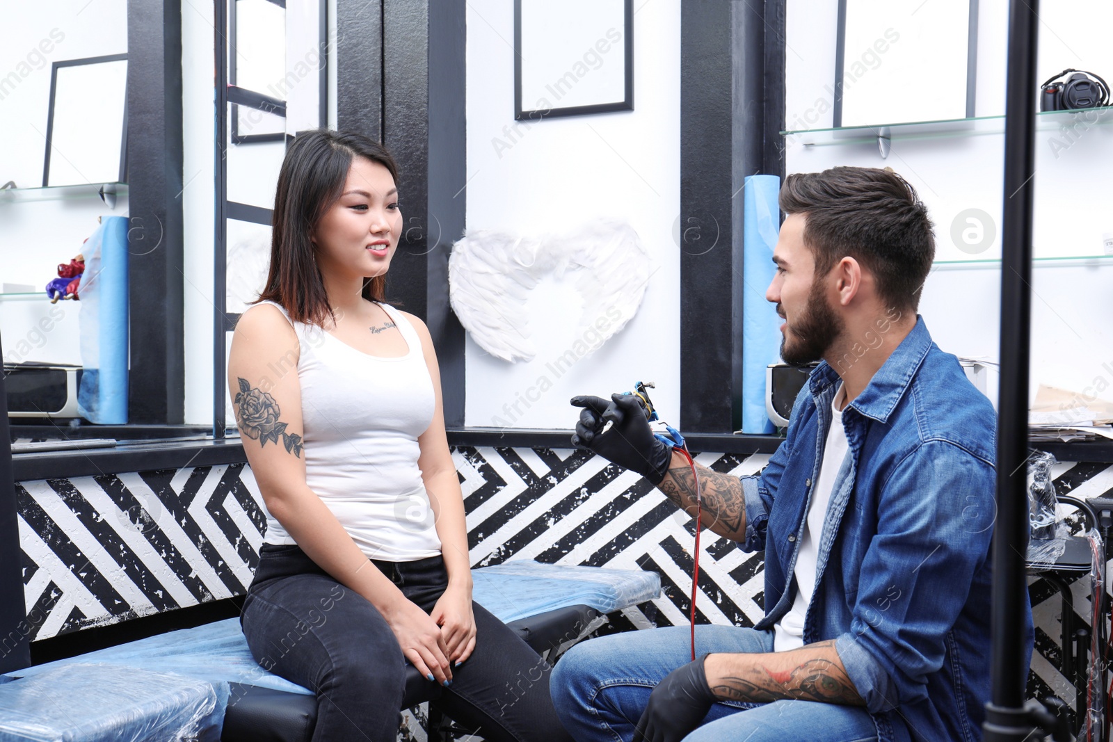 Photo of Professional tattoo artist with client in salon