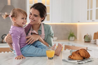 Mother and her little daughter having breakfast together in kitchen