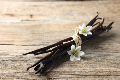 Photo of Bunch of vanilla pods and flowers on wooden table, closeup. Space for text