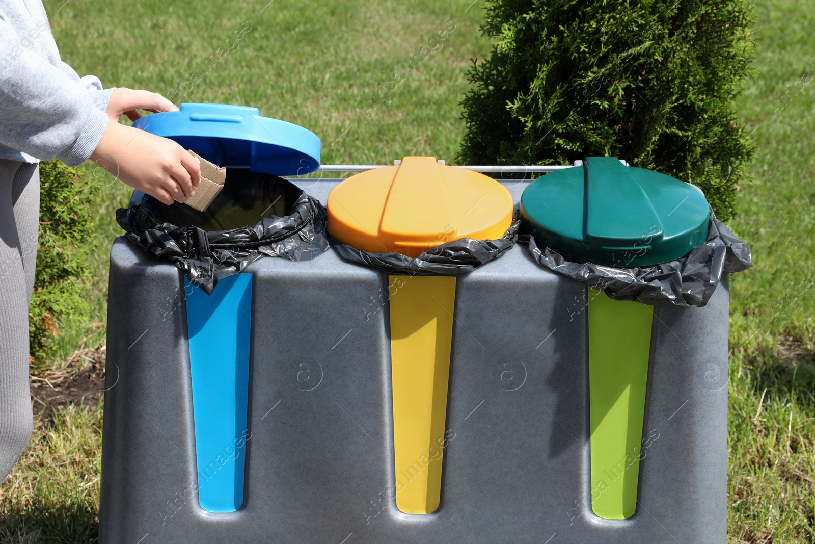 Photo of Woman throwing cardboard in bin outdoors, closeup. Recycling concept