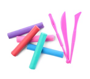 Photo of Many different colorful plasticine pieces and sculpting tools on white background, top view