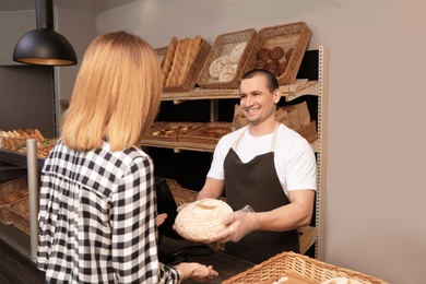 Photo of Woman buying fresh bread in bakery shop