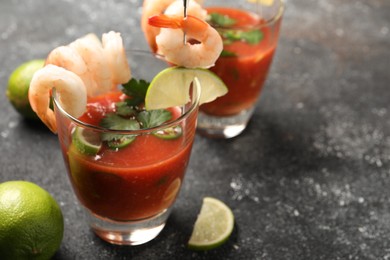 Photo of Tasty shrimp cocktail with sauce in glasses and lime on grey textured table, closeup. Space for text