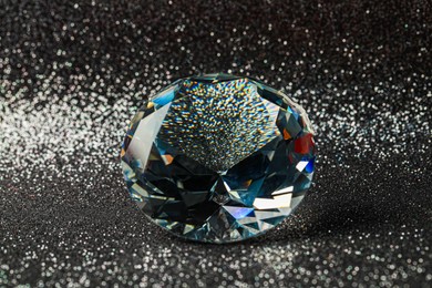 Beautiful dazzling diamond on shiny glitter background, closeup. Precious gemstone