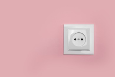 Photo of Power socket on pink wall, space for text. Electrical supply