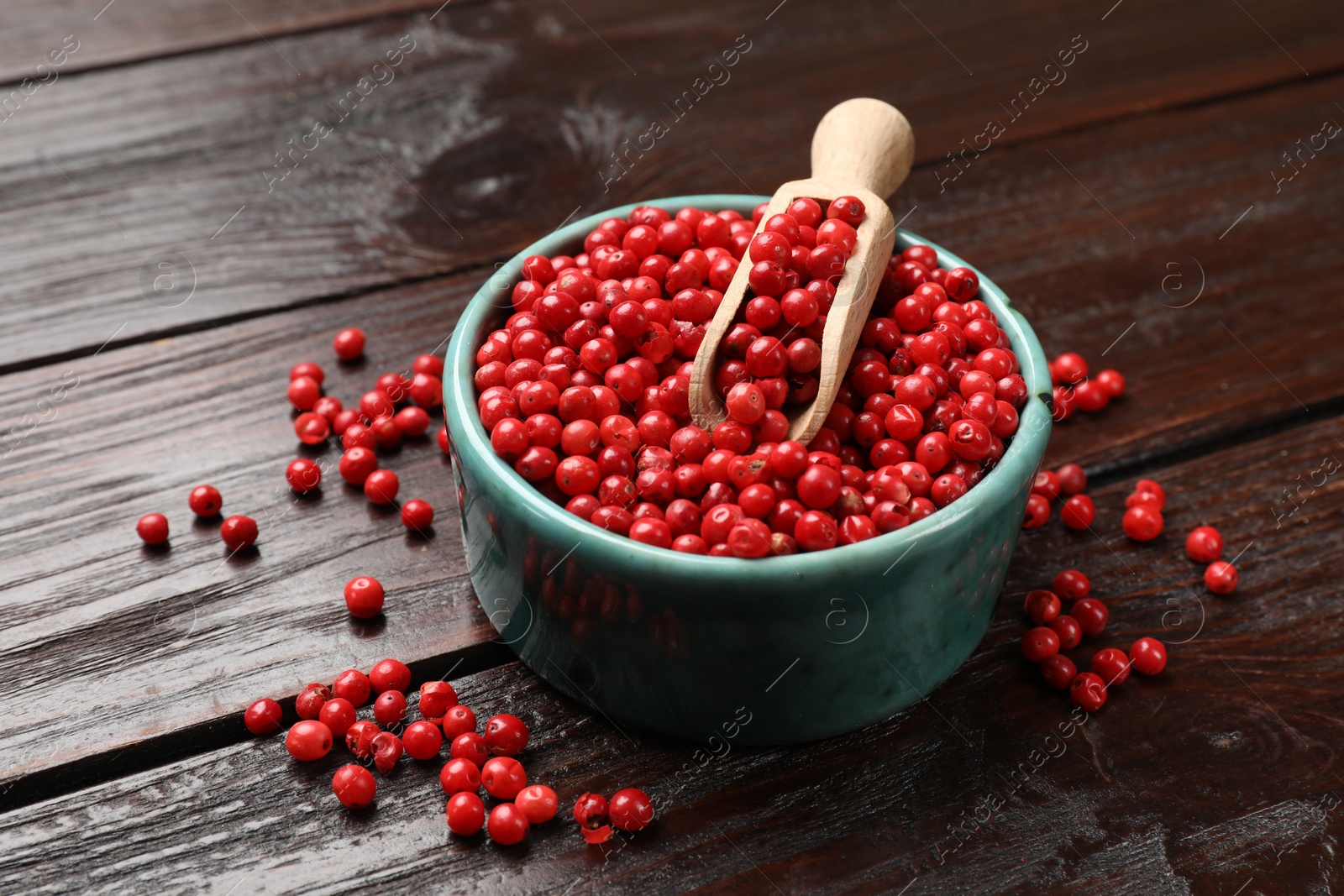 Photo of Aromatic spice. Red pepper in bowl and scoop on wooden table, closeup