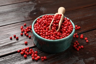 Photo of Aromatic spice. Red pepper in bowl and scoop on wooden table, closeup